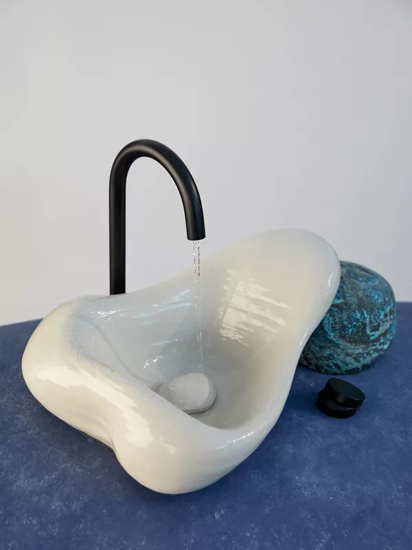 A Rock.01 sink and matte black faucet sitting on top of a large violet stone-like sculpture.